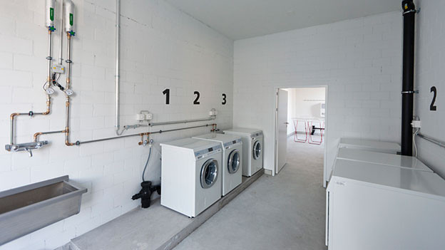 Blick in eine Waschküche mit drei Maschienen.